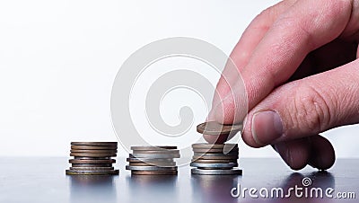 Hand stacking small coins on a table Stock Photo