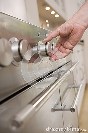 Hand on stove dial in kitchen Stock Photo