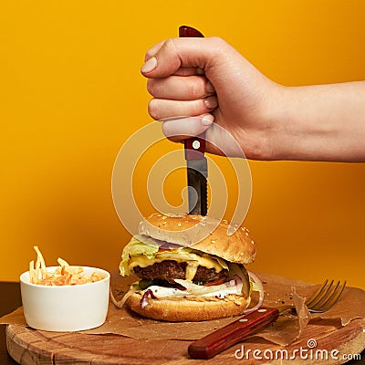 Hand stubbing burger with knife Stock Photo
