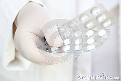 Hand in surgical glove holding pill blisters Stock Photo