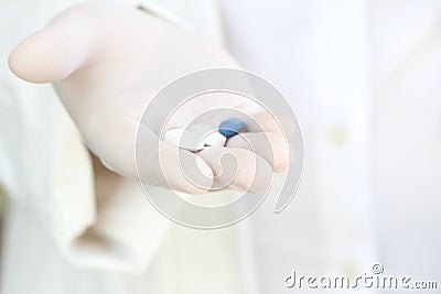 Hand in surgical glove holding pills Stock Photo