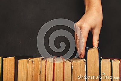 Hand takes a book. Vintage paper library books for reading, education and literature. Knowledge is power Stock Photo