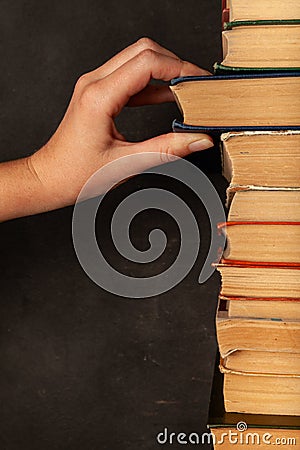 Hand takes a book. Vintage paper library books for reading, education and literature. Knowledge is power Stock Photo