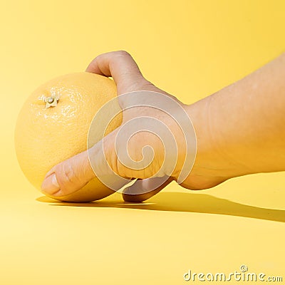Hand takes or puts on the table yellow grapefruit. Setting on a pastel background Stock Photo