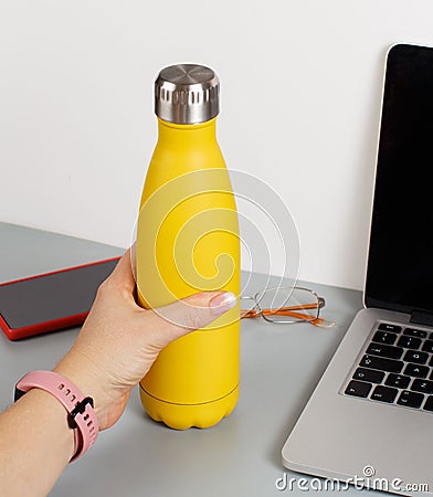 Hand takes yellow insulated bottle Stock Photo