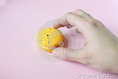 Hand takes yellow macaroon, pink background Stock Photo