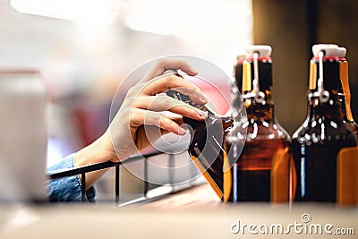 Hand taking bottle of beer from shelf in alcohol and liquor store. Customer buying cider or supermarket staff filling and stocking Stock Photo