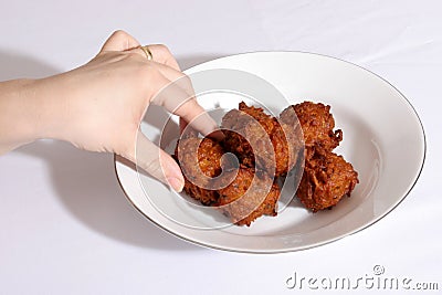 A hand taking a large Indian onion bhajis Stock Photo