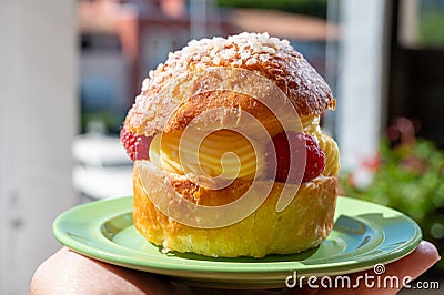 Hand with Tarte tropezienne or La Tarte de Saint-Tropez - dessert pastry consisting of filled brioche with cream and fresh berries Stock Photo