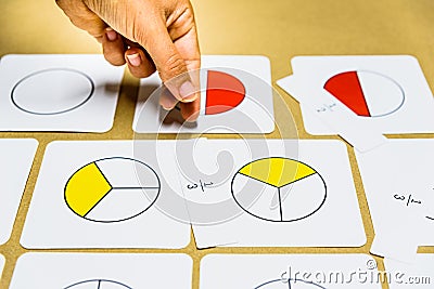 Hand of teacher montessori guide graphically shows fractions with mathematical cards Stock Photo
