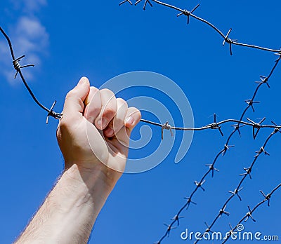 Hand is tearing wire against the blue sky Stock Photo