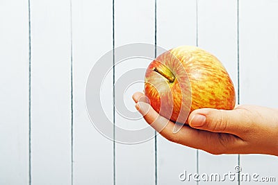 Hand of teenage girl with apple on wooden background with cpy space. Side view. Ecologic clean fresh fruit Stock Photo