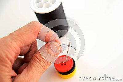 Hand threading a needle with black thread Stock Photo