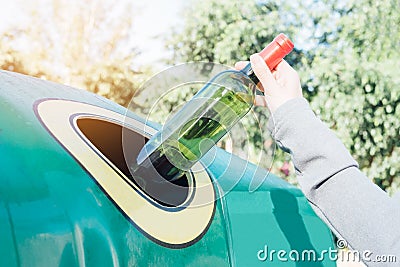 Hand throwing glass bottle in recycling bin Stock Photo