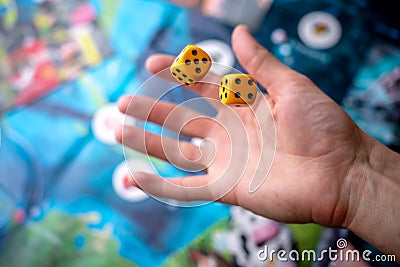 The hand throws two yellow dice on the playing field. The concept of Board games. Gaming moments in dynamics Stock Photo