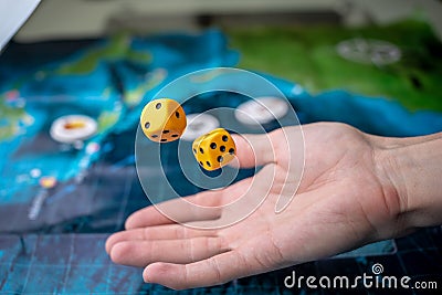 Hand throws yellow dice on the playing field. Luck and excitement. Concept of Board games. Gaming moments in dynamics Stock Photo