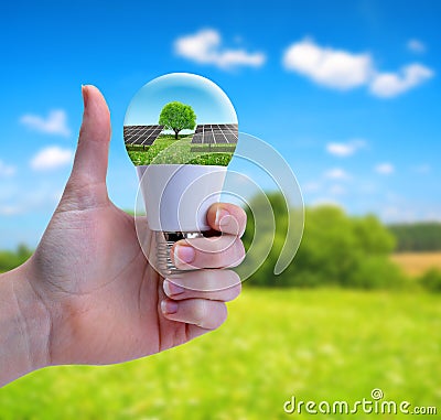 Hand with thumb up holding a eco LED bulb with solar panel. Stock Photo