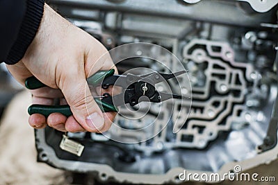 Hand with tool against the background of an automatic transmission with shallow depth of field Stock Photo