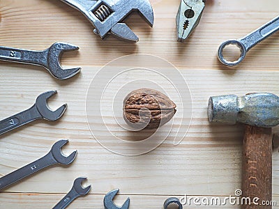 Hand, tool and big walnut on wooden background. The concept of complex problems, the challenge can be solved. Stock Photo
