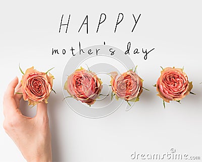 hand touching pink rose buds placed in row with HAPPY MOTHERS DAY inscription Stock Photo