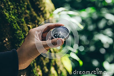 Hand of traveler holding compass in deep forest Stock Photo