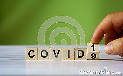 Hand turn wooden cube block with covid19 word. Coronavius Stock Photo