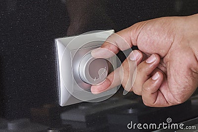 Hand turning down electrical light dimmer switch or conditioner heat controller Stock Photo