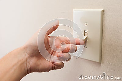 Hand turning wall light switch off. Stock Photo