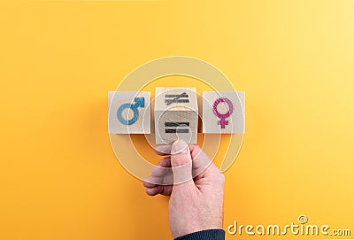 Hand turning wooden cube with symbol unequal to equal between female and male gender icons Stock Photo