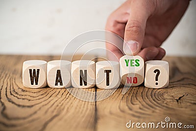 Hand is turning wooden cube with yes an no answer to the question WANT? Stock Photo