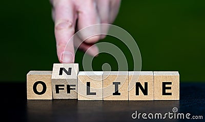 Hand turns cube and changes the word offline to online. Stock Photo