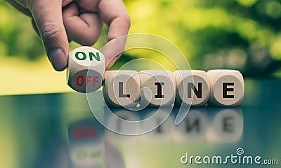 Hand turns a cube and changes the word `offline` to `online`. Stock Photo