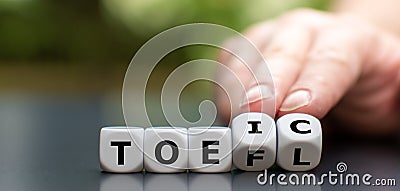Hand turns dice and changes the acronym `toefl` to `toeic`, or vice versa`. Stock Photo