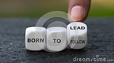 Hand turns dice and changes the expression `born to follow` to `born to lead`. Stock Photo