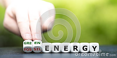 Hand turns dice and changes the expression `fossil energy` to `green energy`. Stock Photo