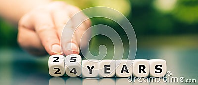 Hand turns dice and changes the expression `24 years` to `25 years`. Stock Photo