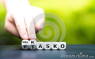 Hand turns dice and changes the German expression `Fiasko` fiasco to `Vollkasko` comprehensive coverage. Stock Photo