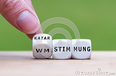 Hand turns dice and changes the German expression `WM Stimmung` world cup atmosphere to `Katar Stimmung` Qatar atmosphere. Stock Photo