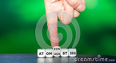 Hand turns dice and changes the German word `Atomausstieg` atomic energy stop to `Atomeinstieg` atomic enegry entrance. Stock Photo