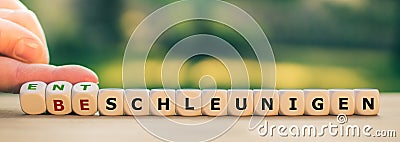 Hand turns dice and changes the German word `beschleunigen` `accelerate` to `entschleunigen` `slow down`. Stock Photo
