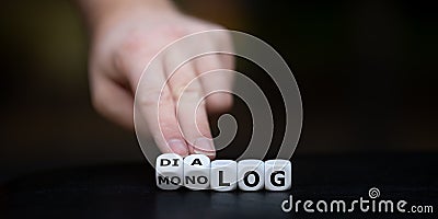 Hand turns dice and changes the German word `Monolog` monologue to `Dialog` dialogue. Stock Photo