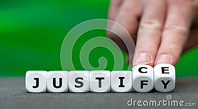 Hand turns dice and changes the word justify to justice. Stock Photo