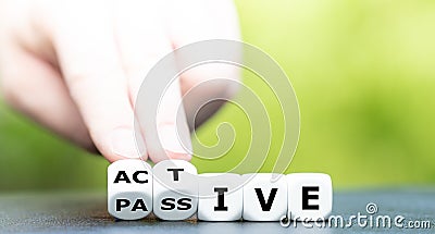 Hand turns dice and changes the word passive to active Stock Photo