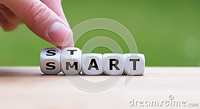 Hand turns dice and changes the word `start` to `smart`. Stock Photo