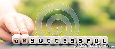 Hand turns dice and changes the word `unsuccessful` to `successful`. Stock Photo