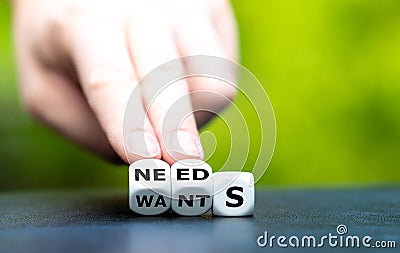 Hand turns dice and changes the word wants to needs. Stock Photo