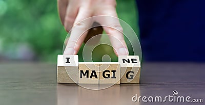 Hand turns wooden cubes and changes the word magic to imagine Stock Photo