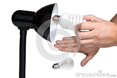 Hand twists bulb in lighting Stock Photo