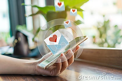 Hand typing love letter email in smartphone social network online community with social media love letter mail send out icons Stock Photo