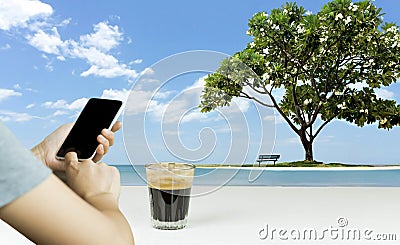 Hand using cell phone and coffee with beautiful frangipani tree Stock Photo